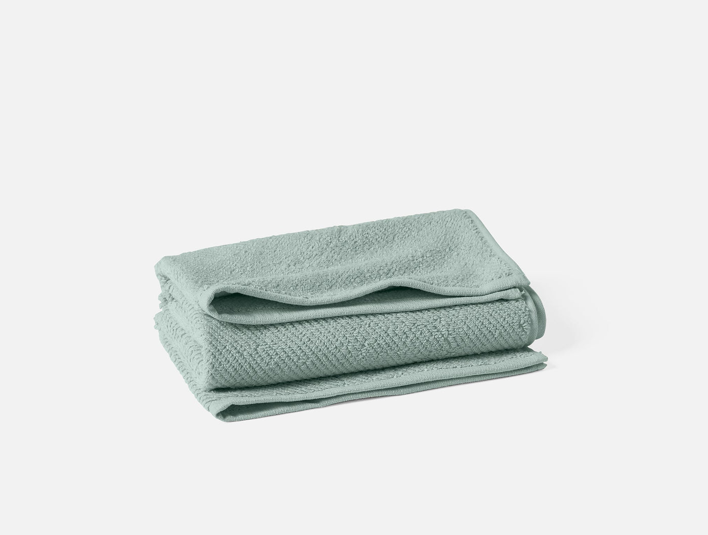 Coyuchi Air Weight wash cloth in sage, folded stack showing subtle woven texture.