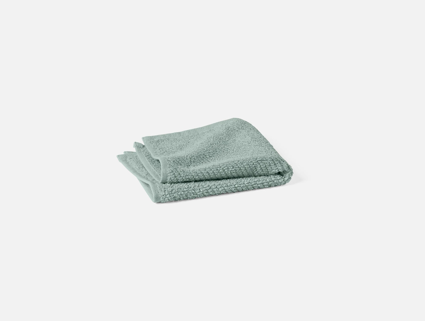 Close-up of folded sage green Coyuchi Air Weight bath sheet showing textured weave.