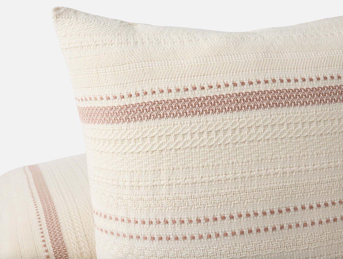 Close-up of Coyuchi Bonita pillow corner showing rose stripe embroidery on ivory woven cotton.