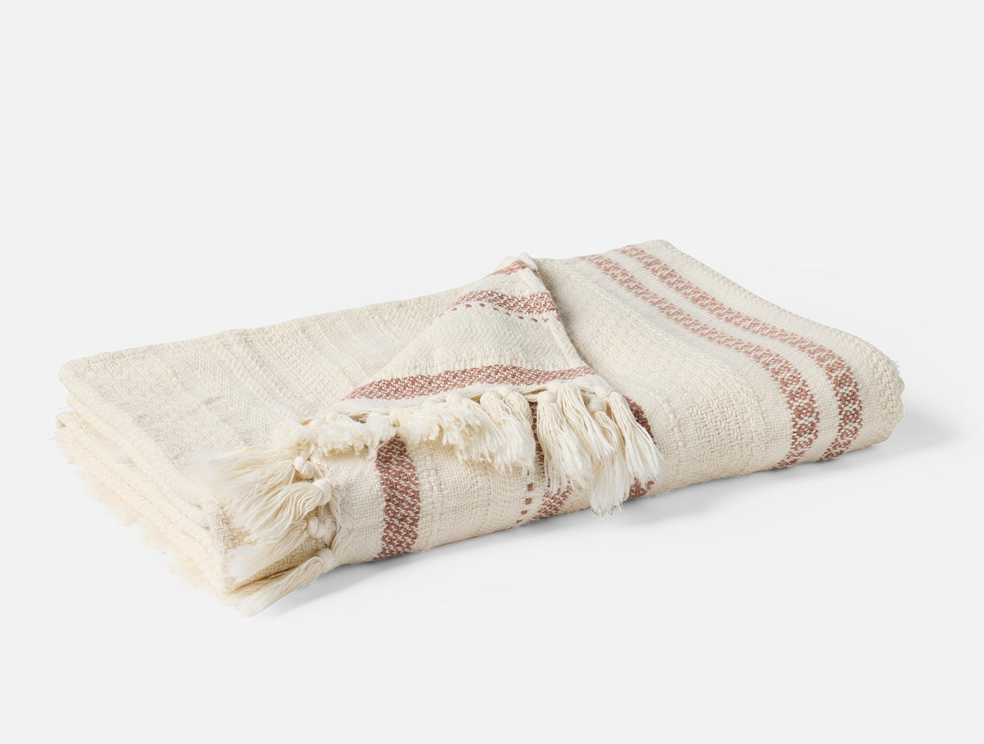 Folded Coyuchi Bonita throw in ivory with terracotta stripe detail and fringe trim.