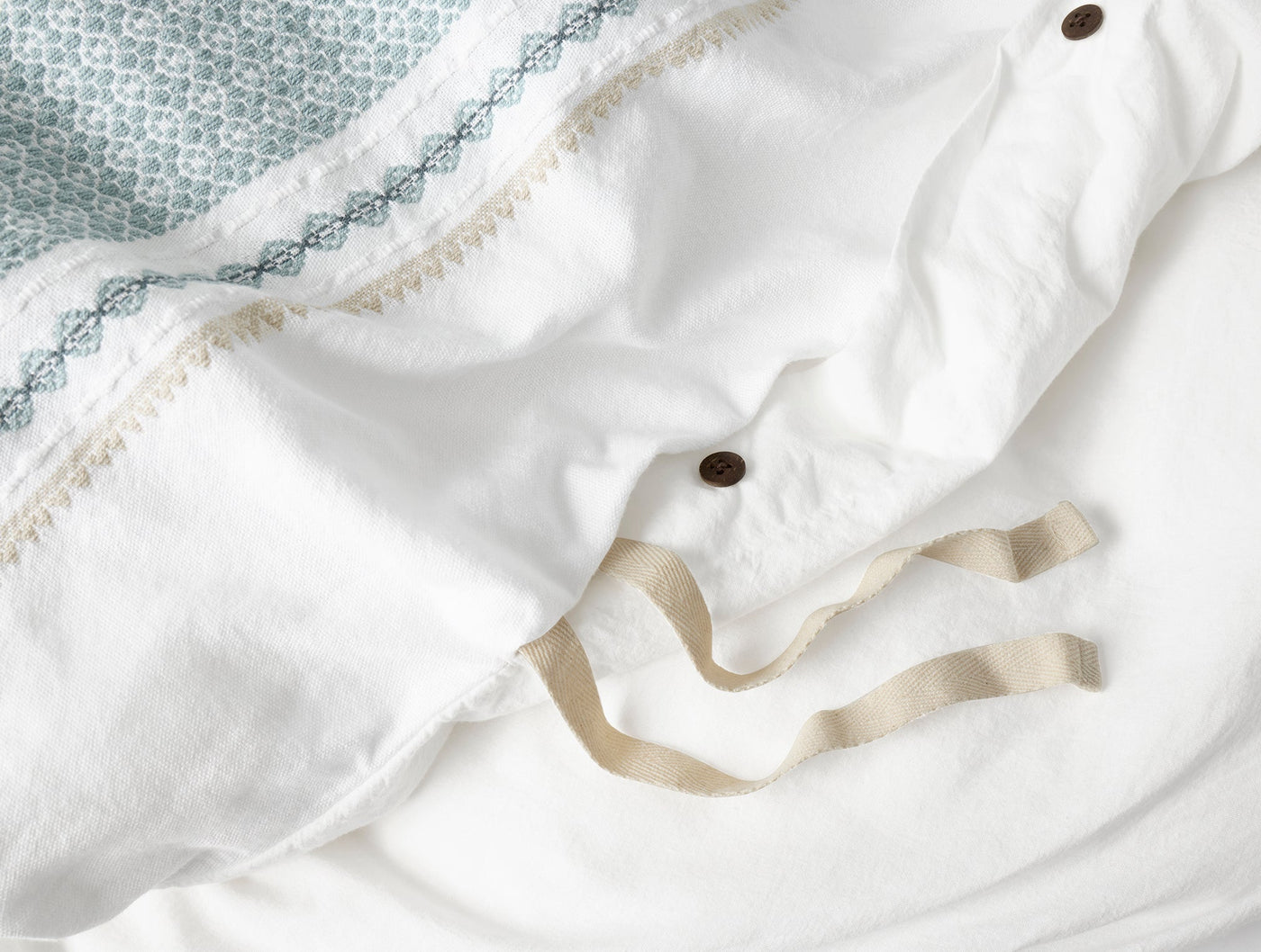 Close-up of Coyuchi Cabrillo duvet cover interior ties and button closure in natural linen.