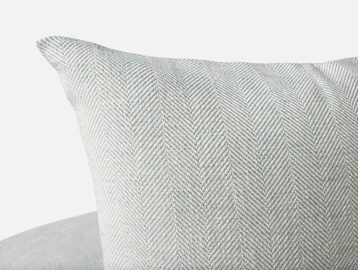 Close-up of Coyuchi Canyon pillow cover showing sage herringbone weave texture and corner detail.