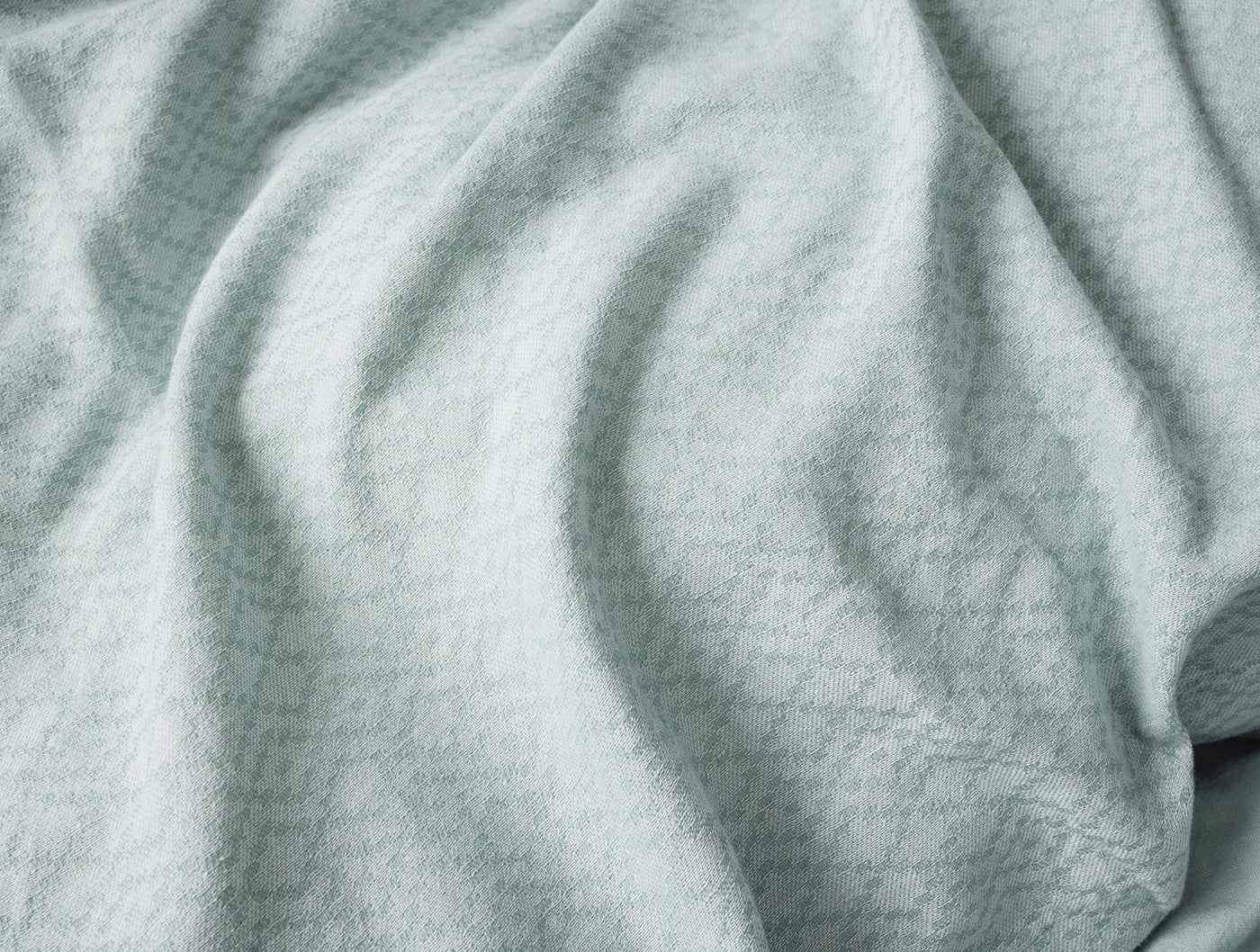 Close-up of draped seafoam Coyuchi Capitola duvet cover showing subtle woven texture.