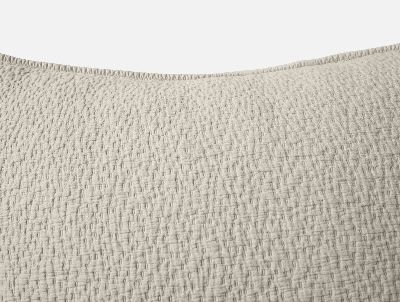 Close-up of Coyuchi Cascade Matelasse sham in natural, showing woven texture and stitched edge.