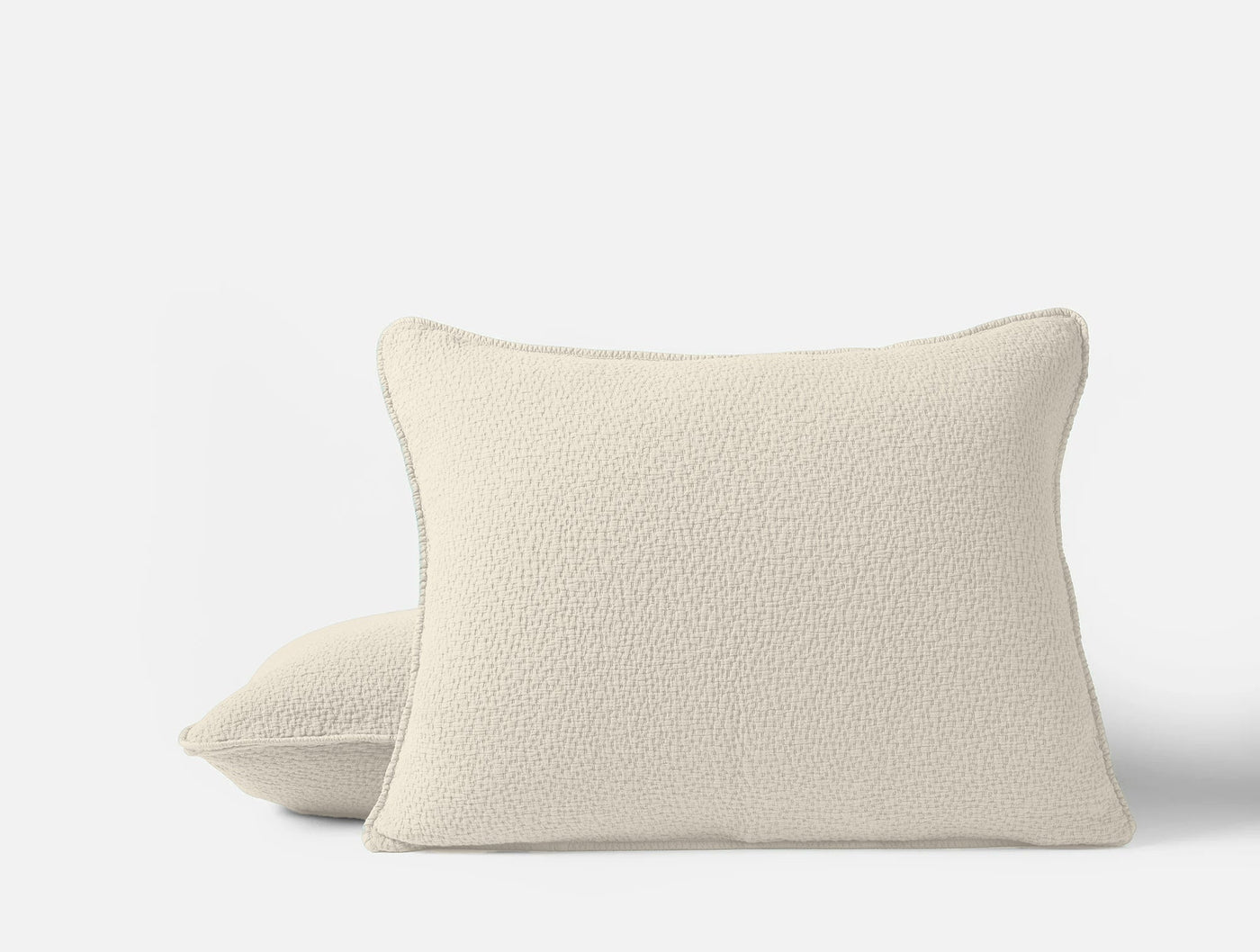 Pair of Coyuchi Cascade Matelassé shams in ivory, boucle-textured fabric, stacked view.