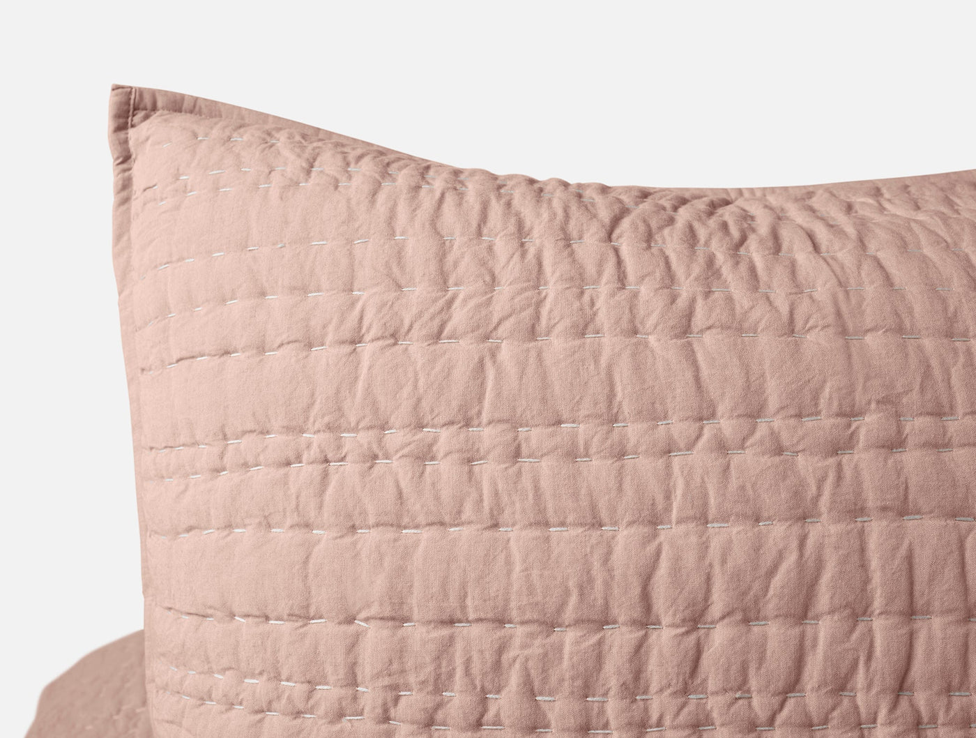 Close-up of blush Channel Handstitched sham corner showing grid quilting texture.