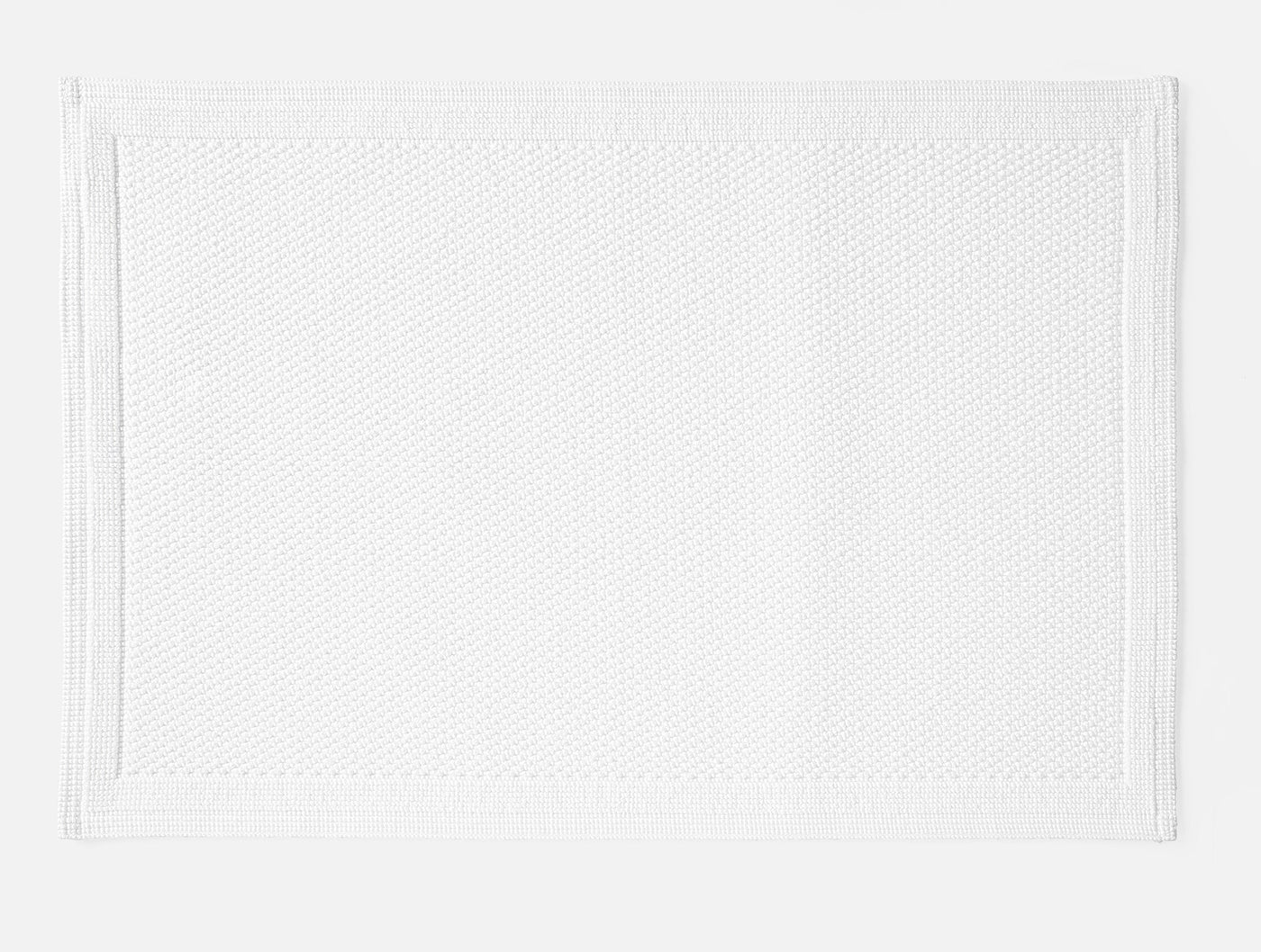 Coyuchi Cove bath rug in white with textured weave and bordered edge detail.
