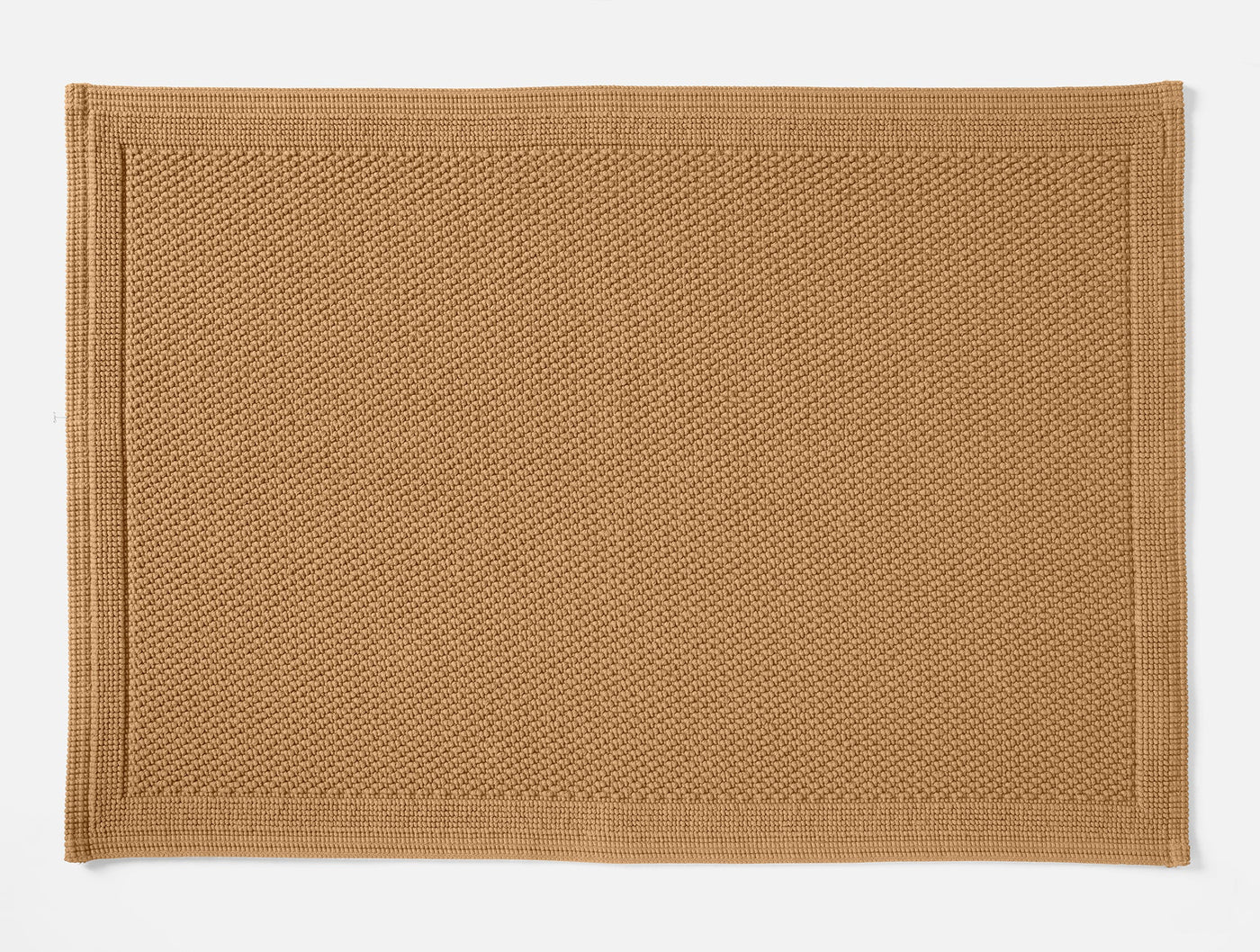 Coyuchi Cove bath rug in camel, close-up of honeycomb texture weave with bordered edge.
