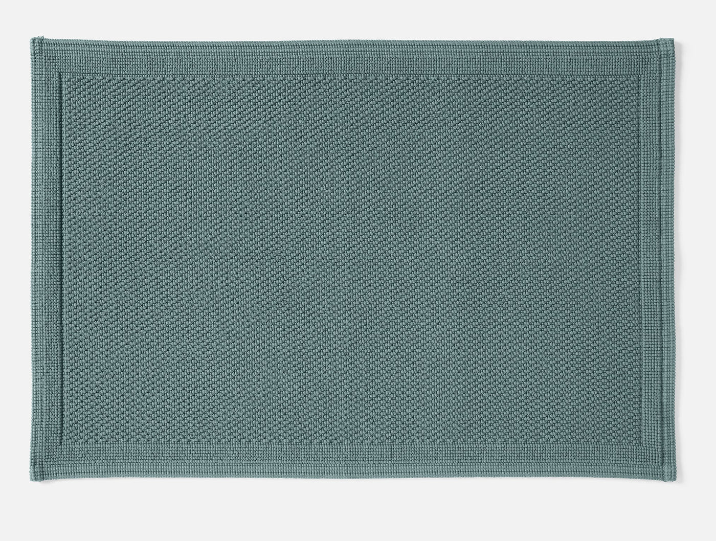Close-up of Coyuchi Cove bath rug in slate blue, showing nubby cotton texture and border detail.