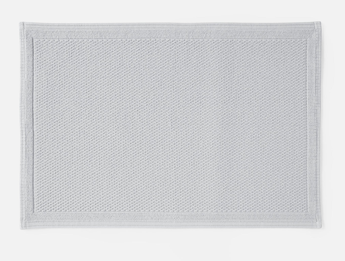 Coyuchi Cove bath rug in silver, showing textured weave and bordered edge detail.