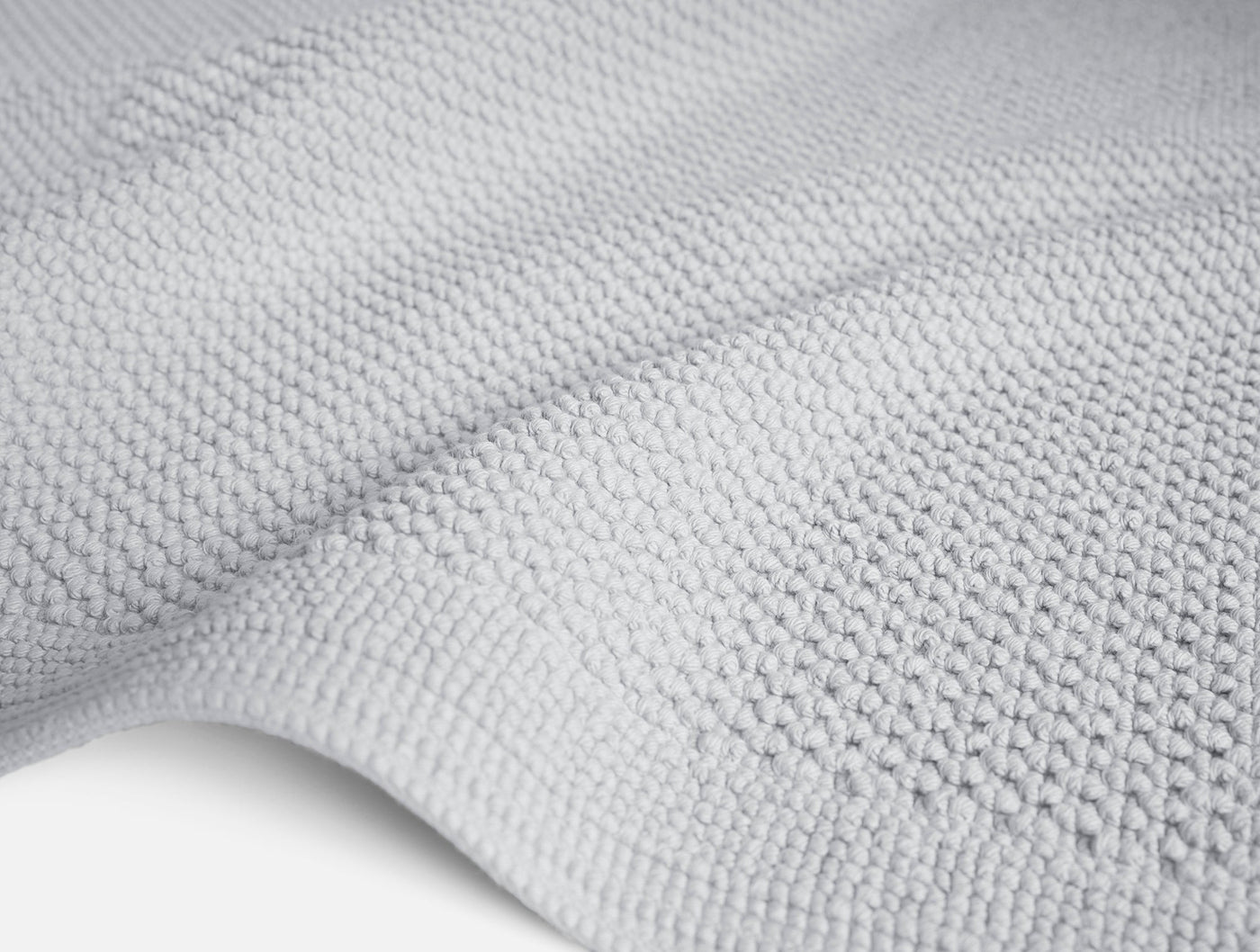 Close-up of Coyuchi Cove bath rug in silver grey, showing nubby cotton weave texture.