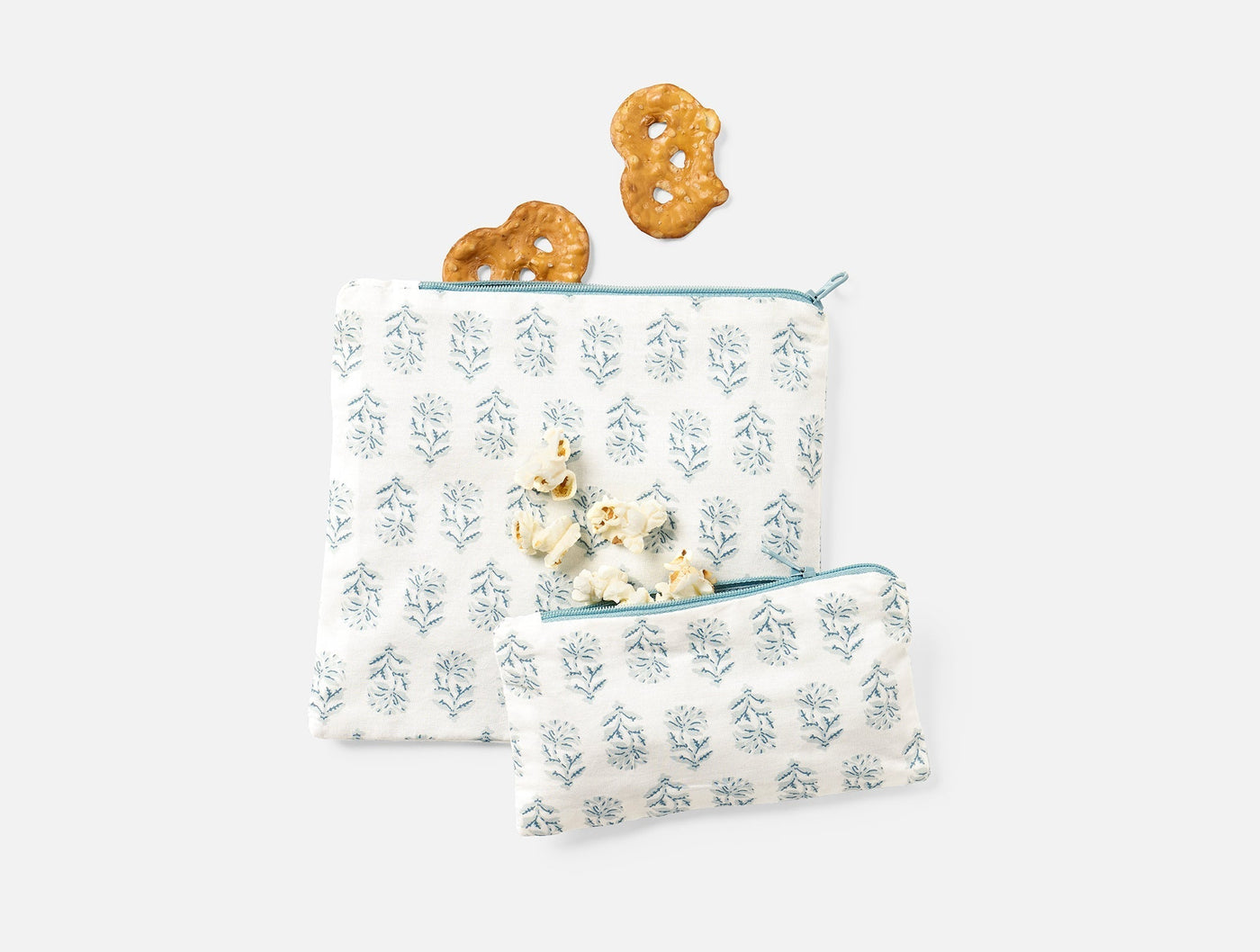 Two Coyuchi Conserve snack bags in white with blue floral block print, styled with crackers.