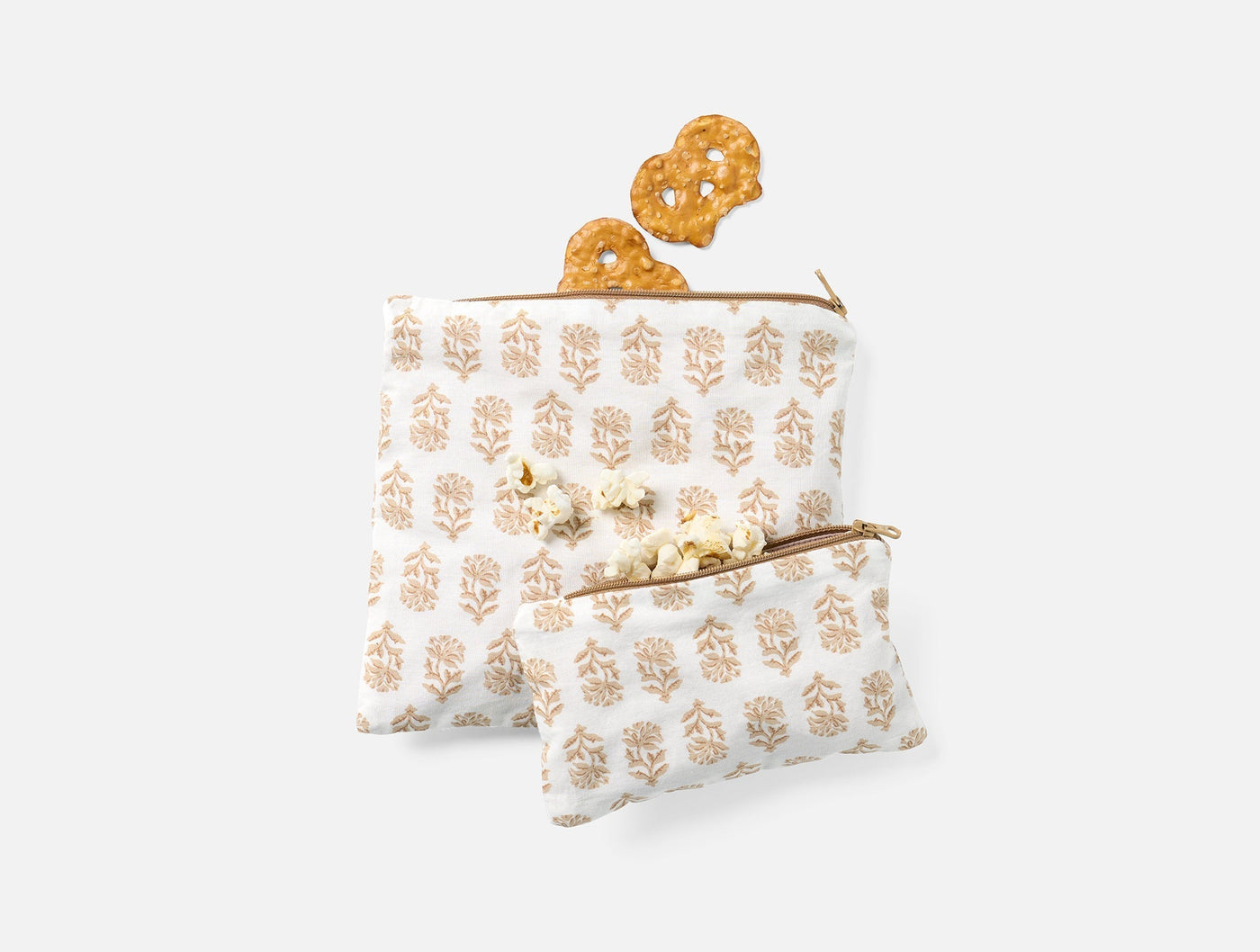 Two Coyuchi Conserve snack bags in white with tan block print botanicals, styled with crackers.