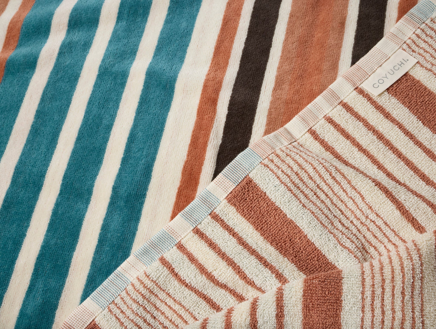 Coyuchi Morelia beach towel corner folded back, showing terry front and flat-woven reverse stripe.