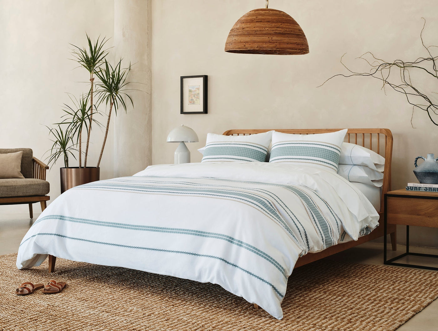Cabrillo duvet cover styled on bed with teal stripes, natural wood frame, and warm neutral room.