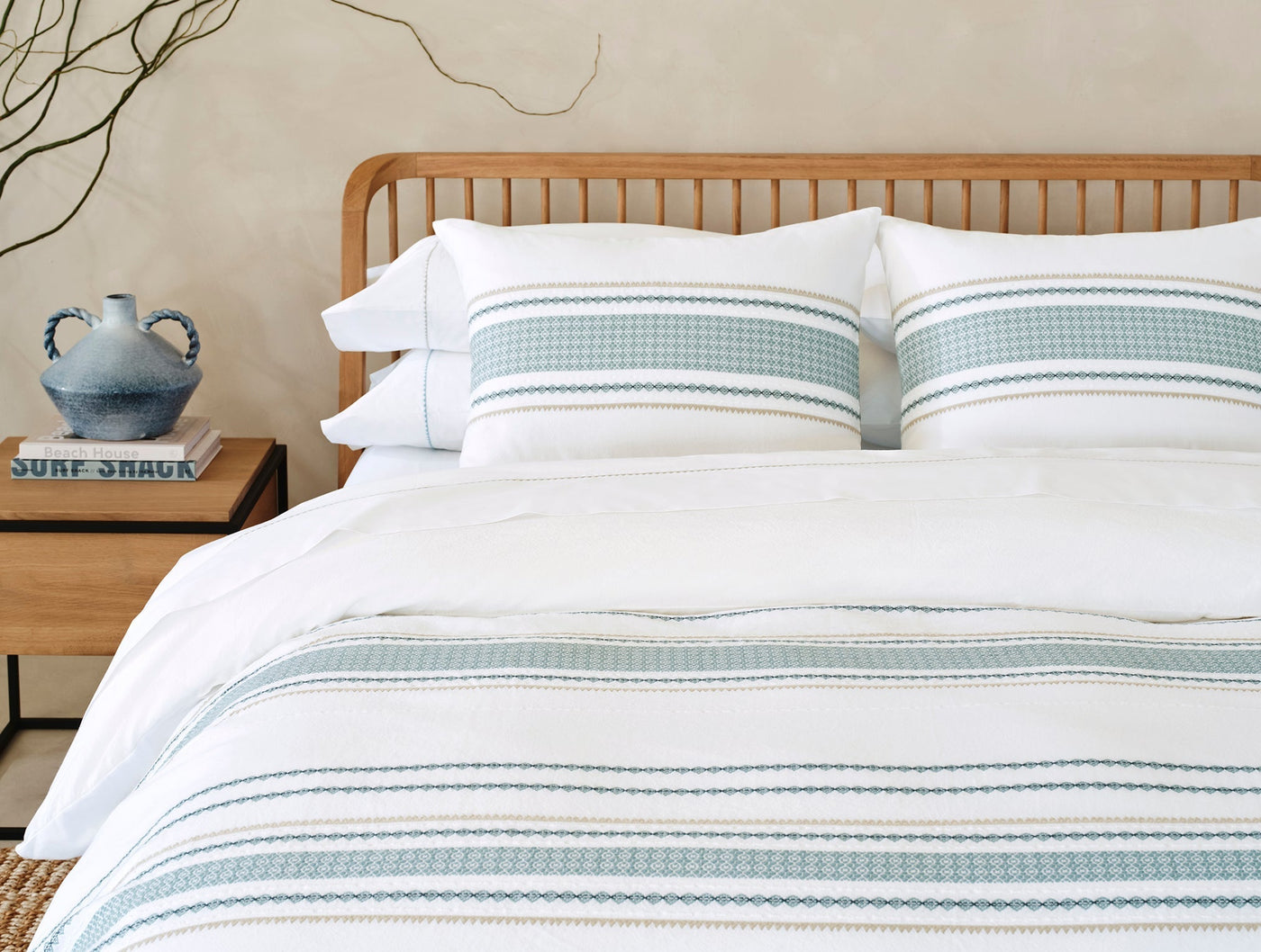 Styled bed with Cabrillo duvet cover featuring sage green embroidered stripes on white.