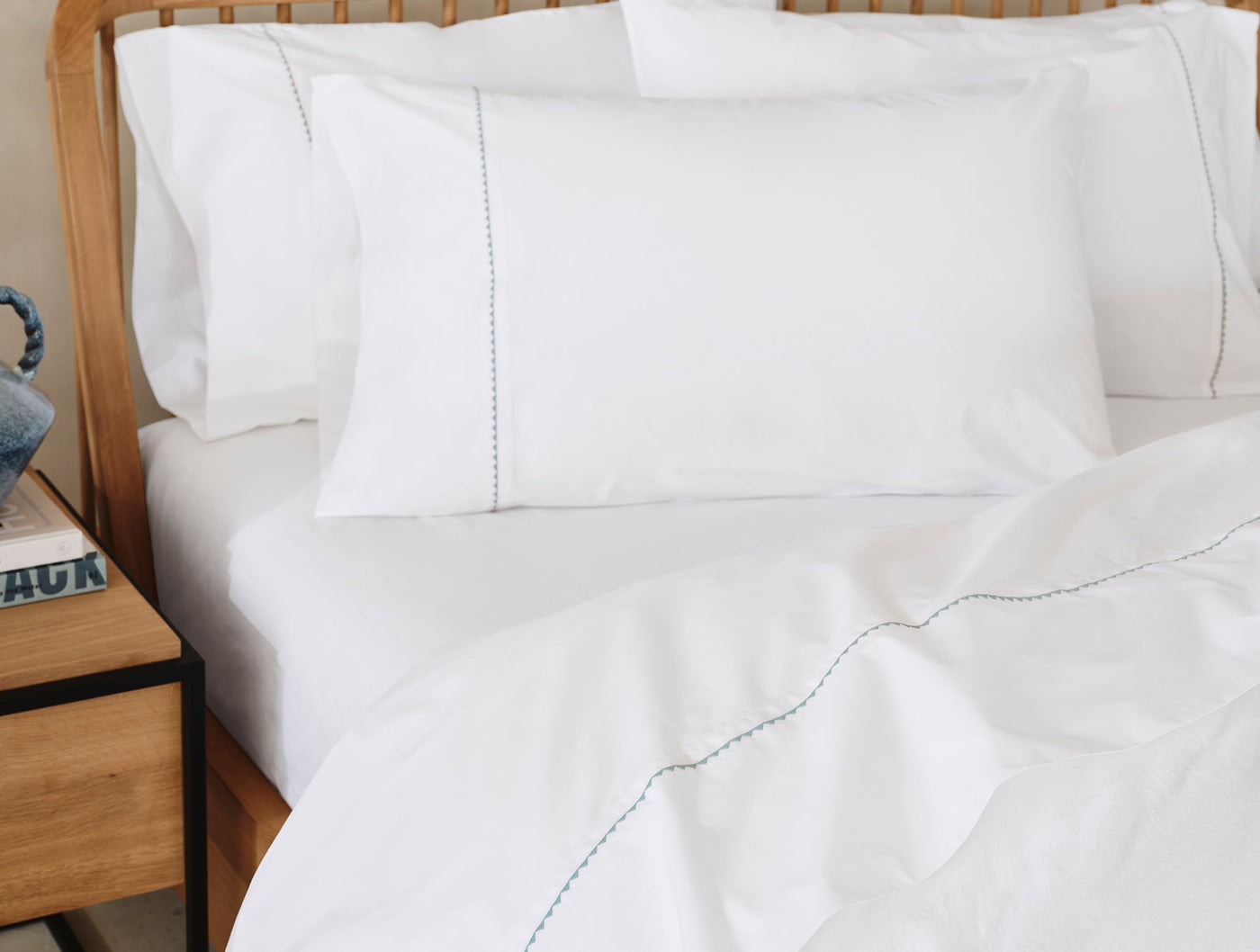 White Coyuchi pillowcases with delicate trailing embroidered detail, styled on a made bed.