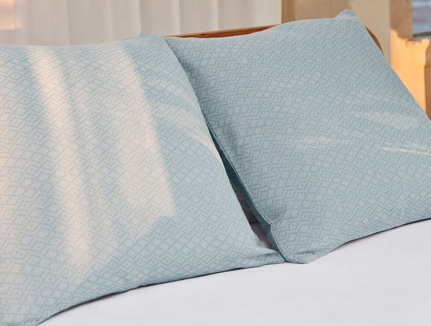 Two duck egg blue Coyuchi Capitola shams with diamond jacquard pattern on a made bed.