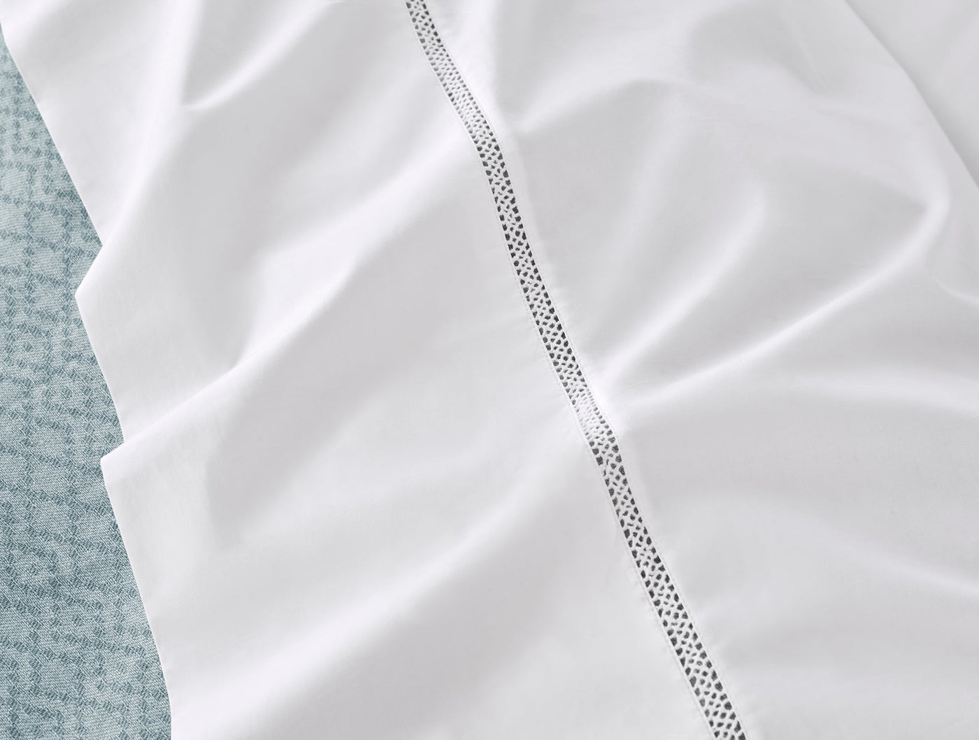 Close-up of white percale sheet with delicate lattice hemstitch trim detail.