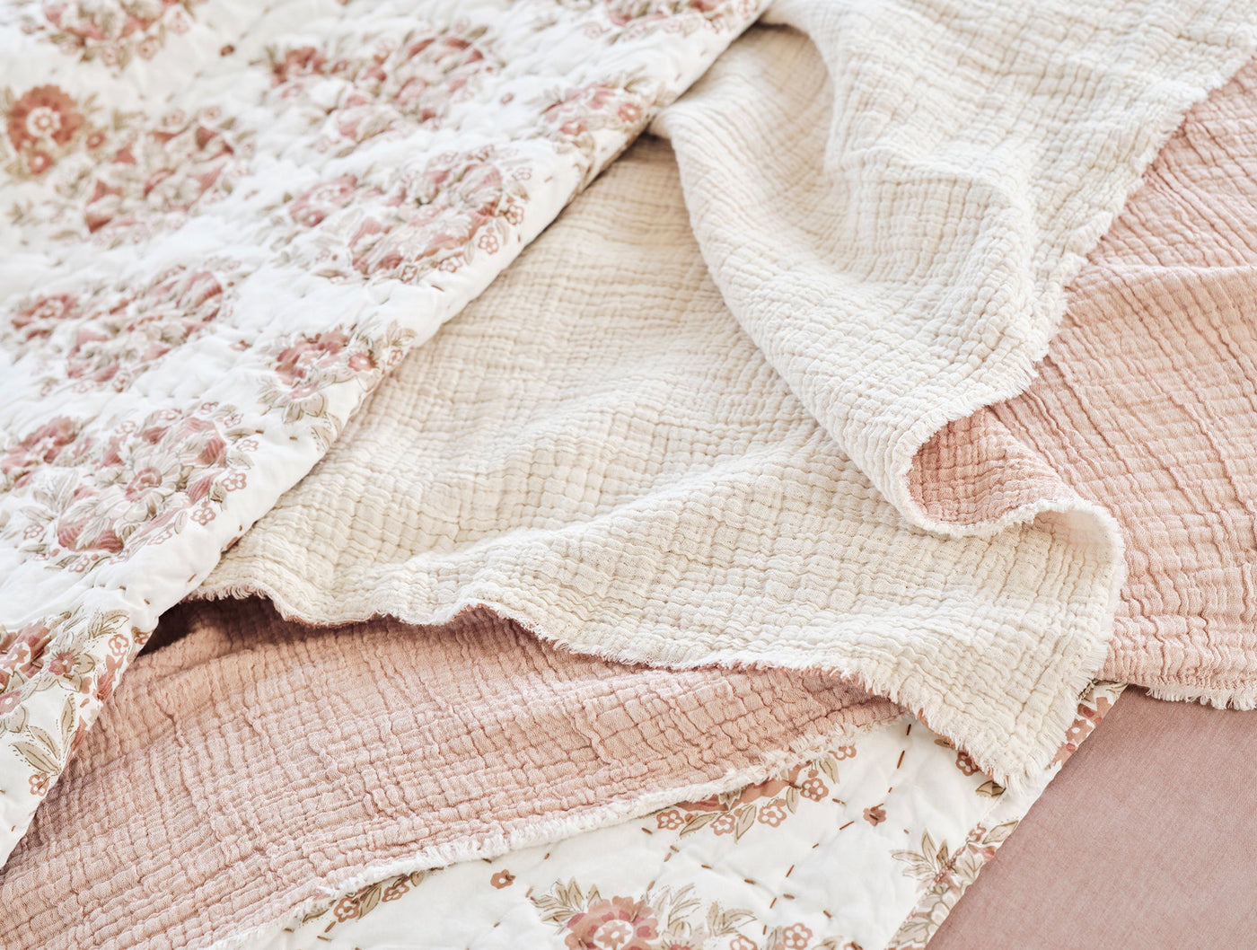 Close-up of ivory matelassé weave texture with blush floral quilted layers beneath.