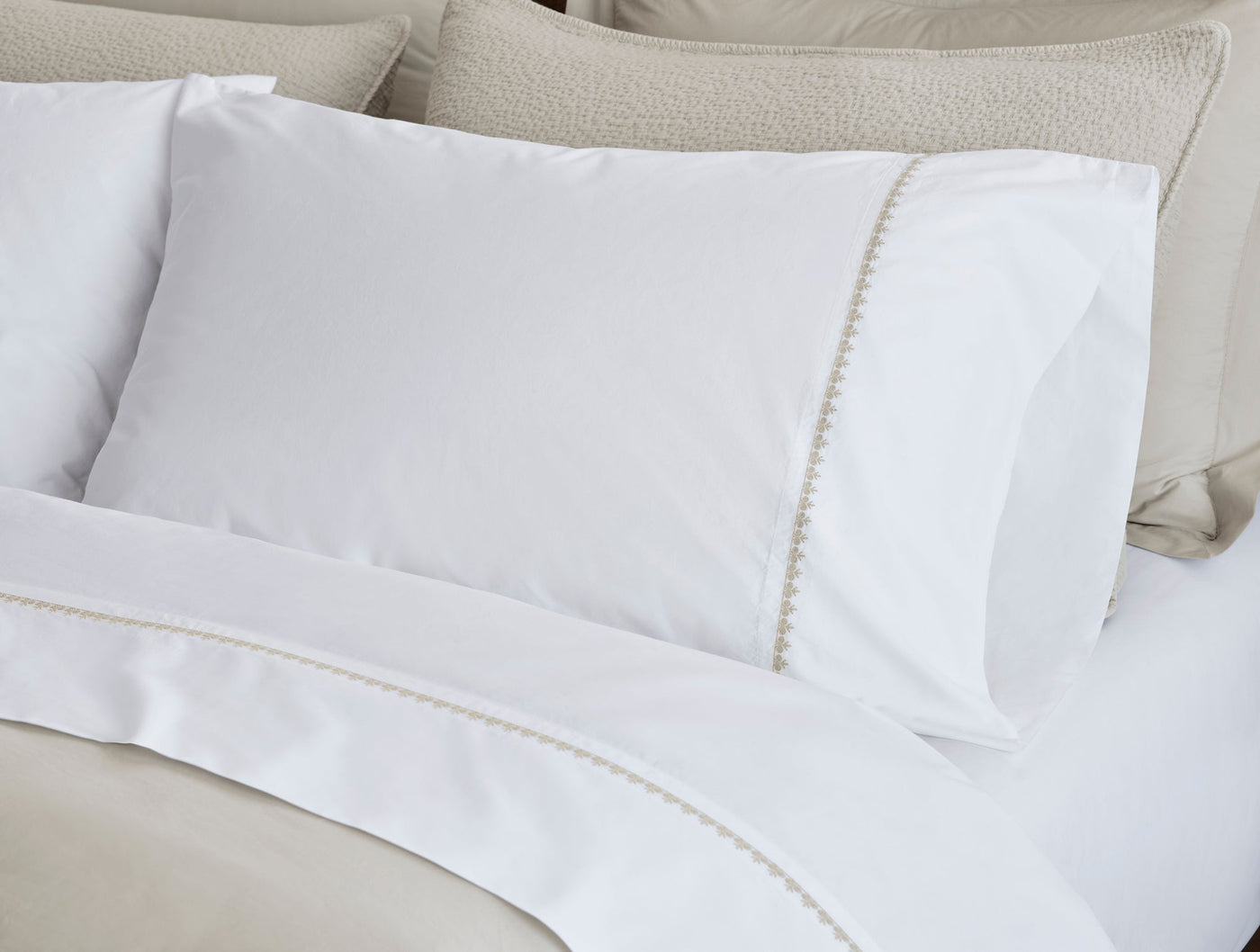 Close-up of white Coyuchi Floret sheet set with ivory embroidered floral trim detail.