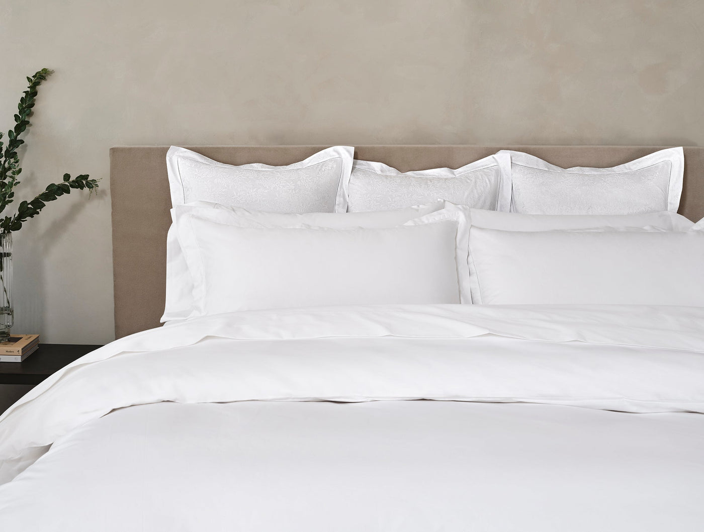 Bed styled with white Heirloom Sateen duvet and layered pillows against a neutral headboard.
