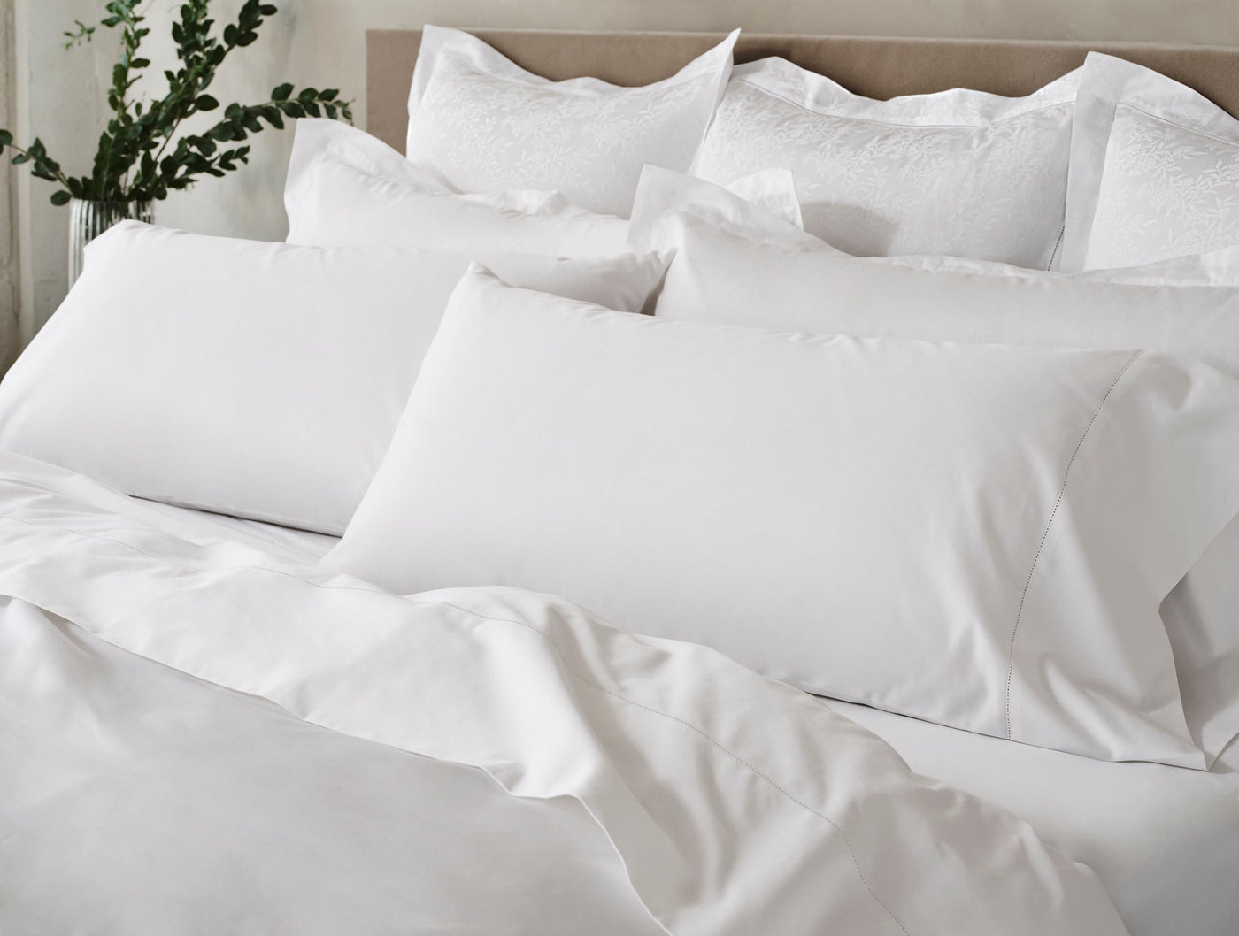 Coyuchi Heirloom Sateen white pillowcases and duvet styled on a bed, soft sheen finish.