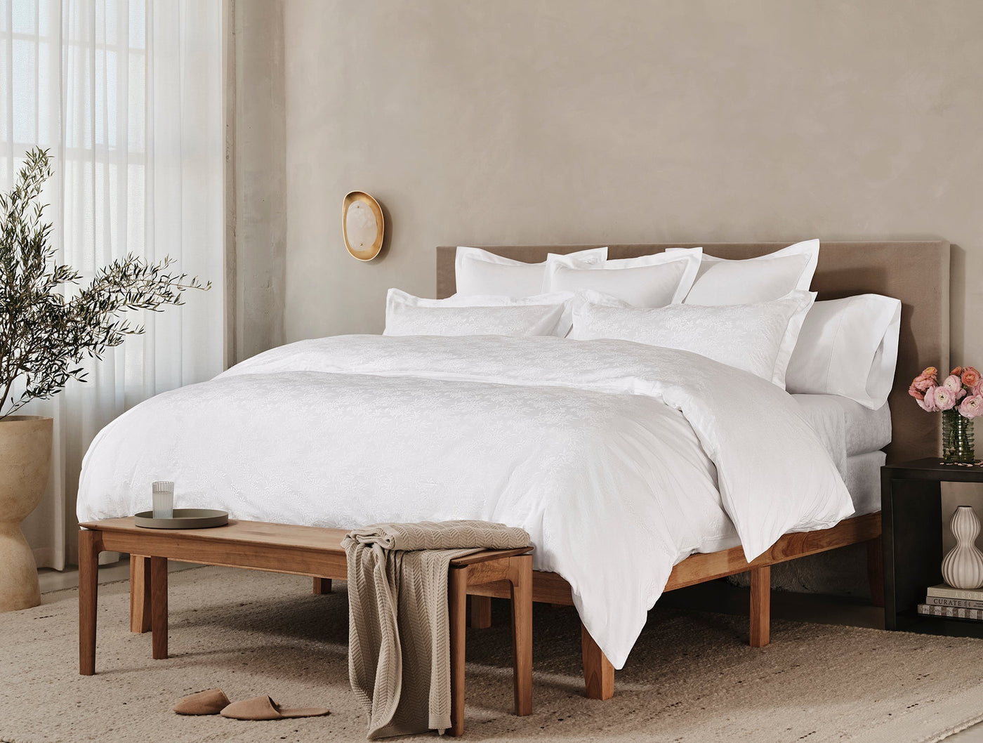 Coyuchi Heirloom Sateen Jacquard duvet cover in white styled on a bed in a neutral bedroom.