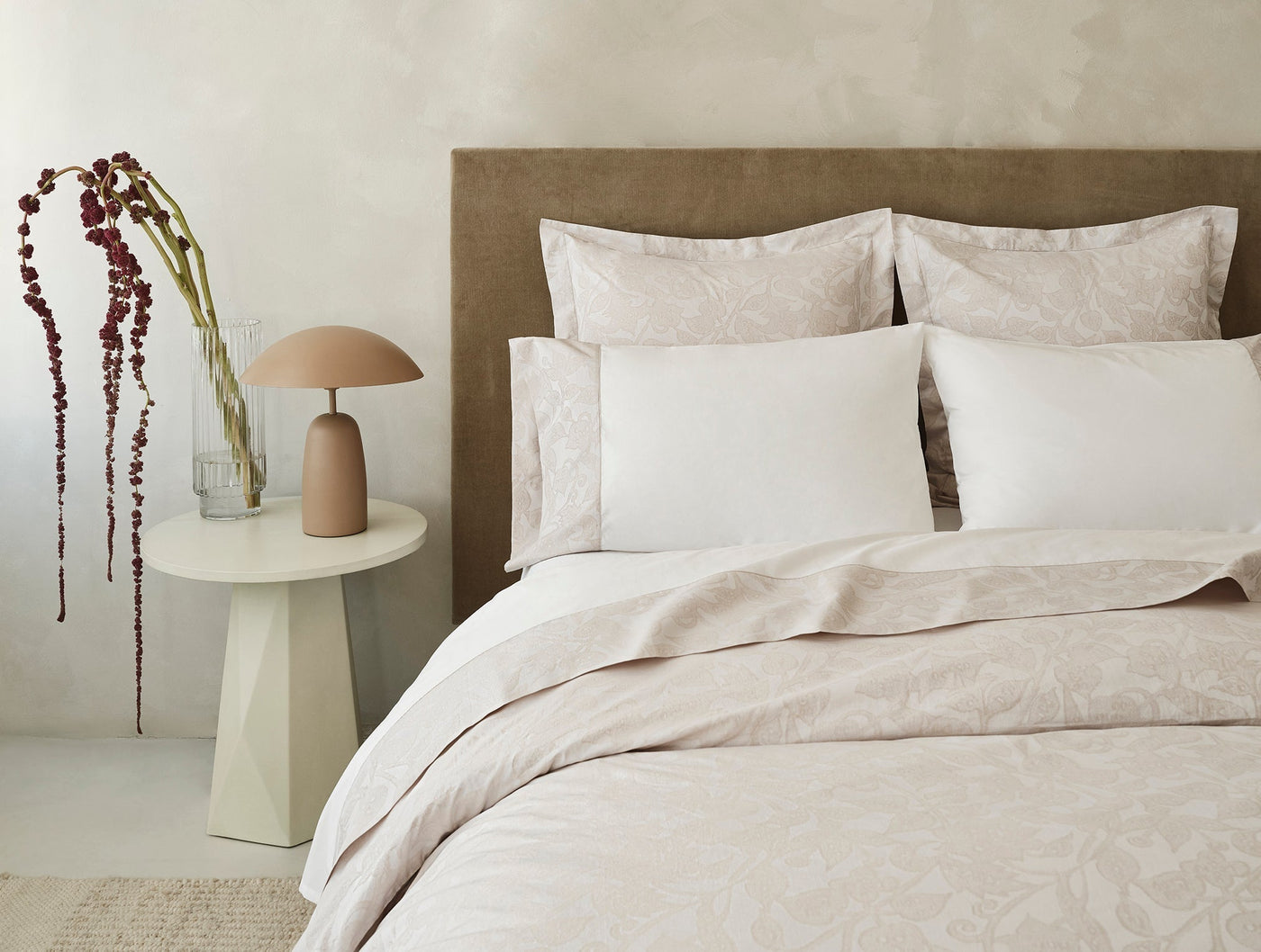 Duvet cover draped over bed with subtle jacquard botanical pattern in blush, styled with white pillows.