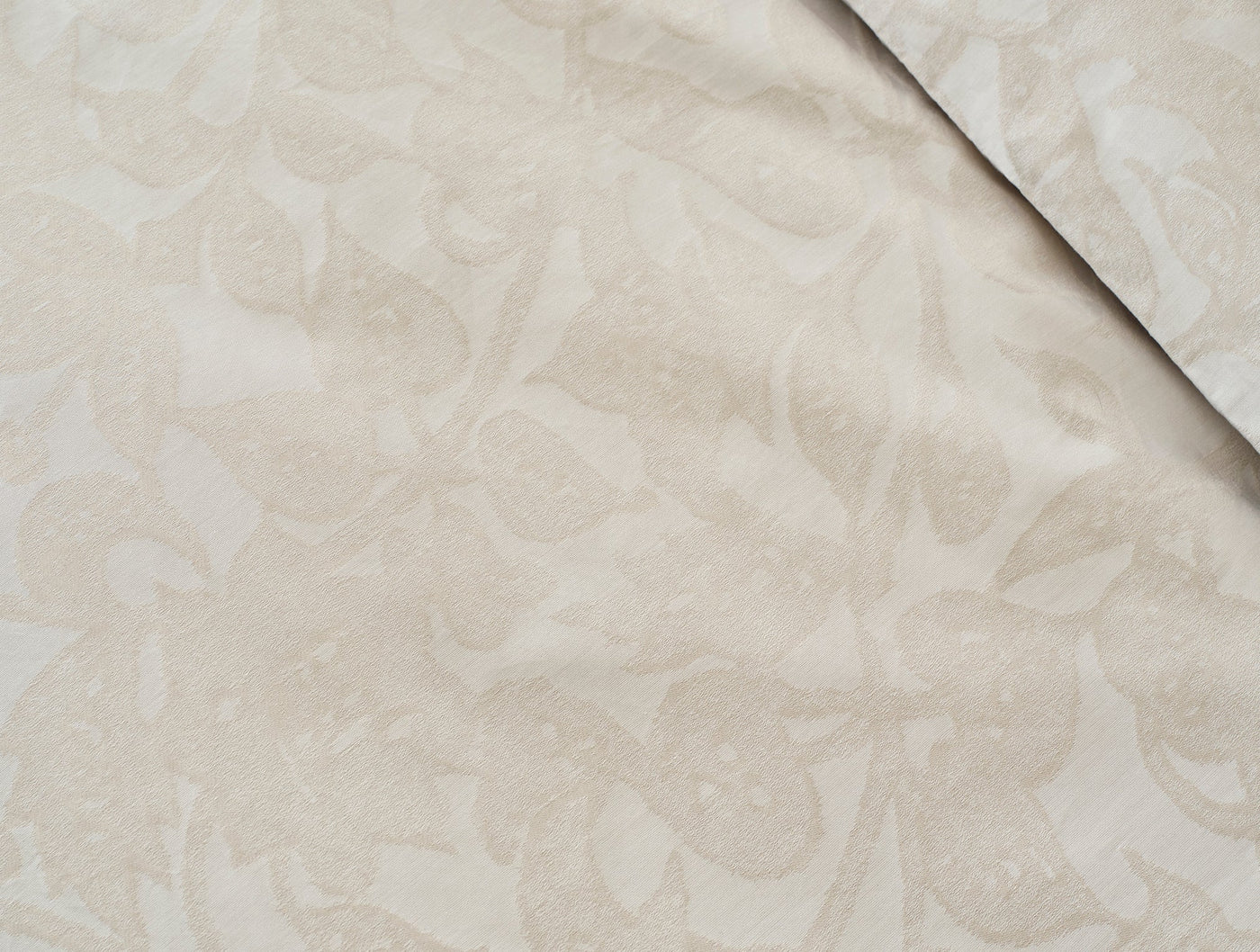 Close-up of ivory jacquard weave with tone-on-tone floral motif and folded edge detail.