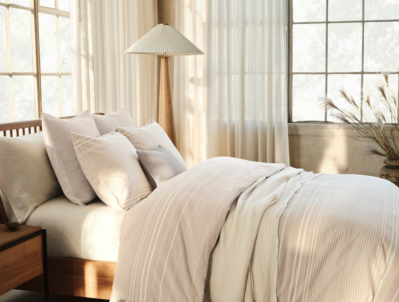 Coyuchi Little Sur Stripe duvet set styled on bed in warm, sunlit bedroom.