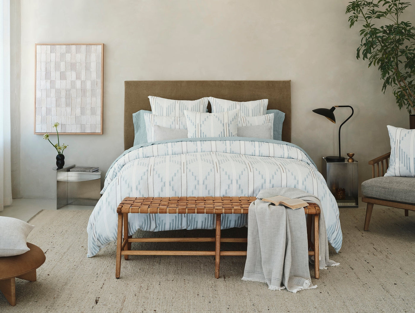 Morelia duvet cover styled on bed with woven bench, natural tones, soft blue pattern.