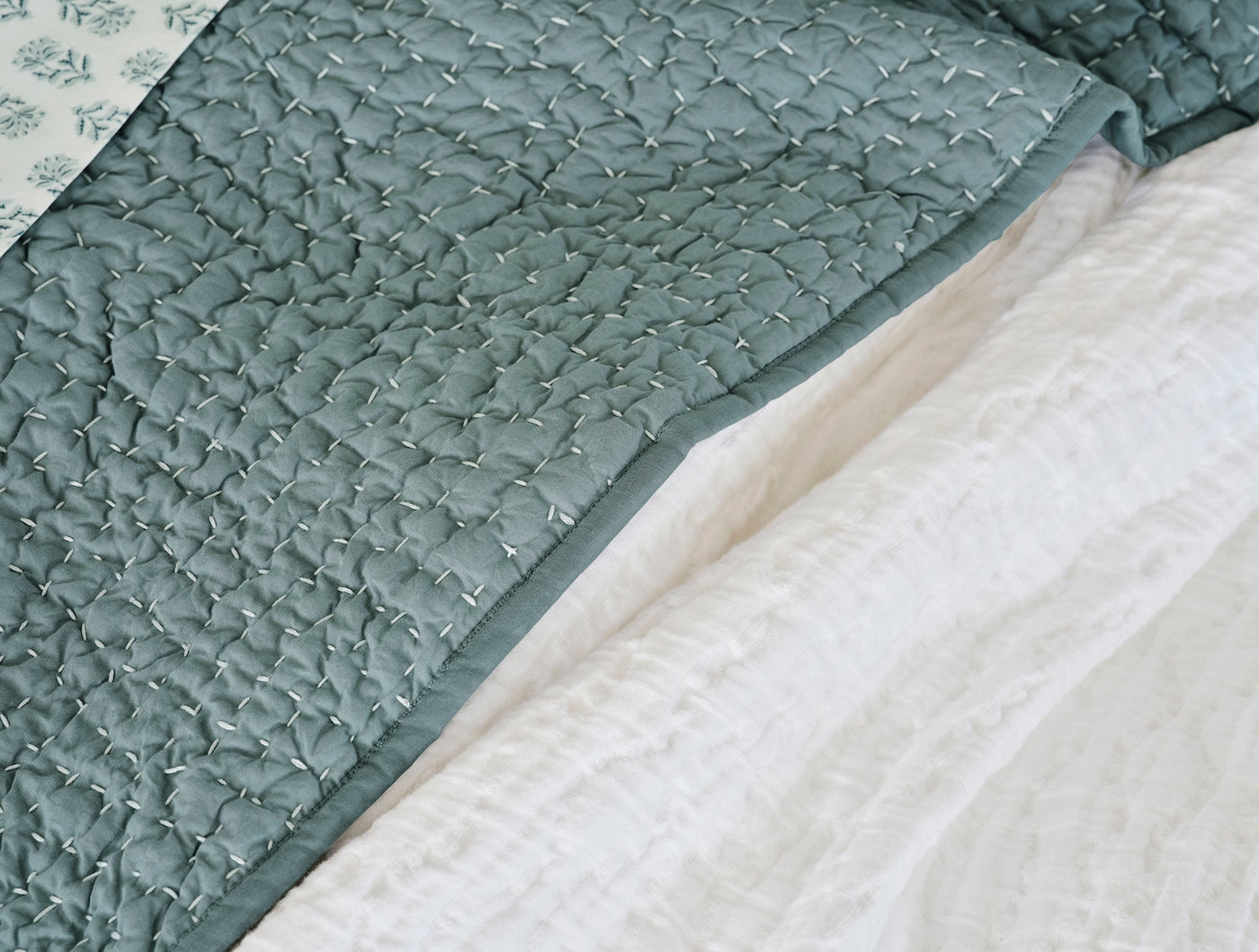 Close-up of Coyuchi Pebbled Handstitched quilt edge in slate, showing organic stitch texture.