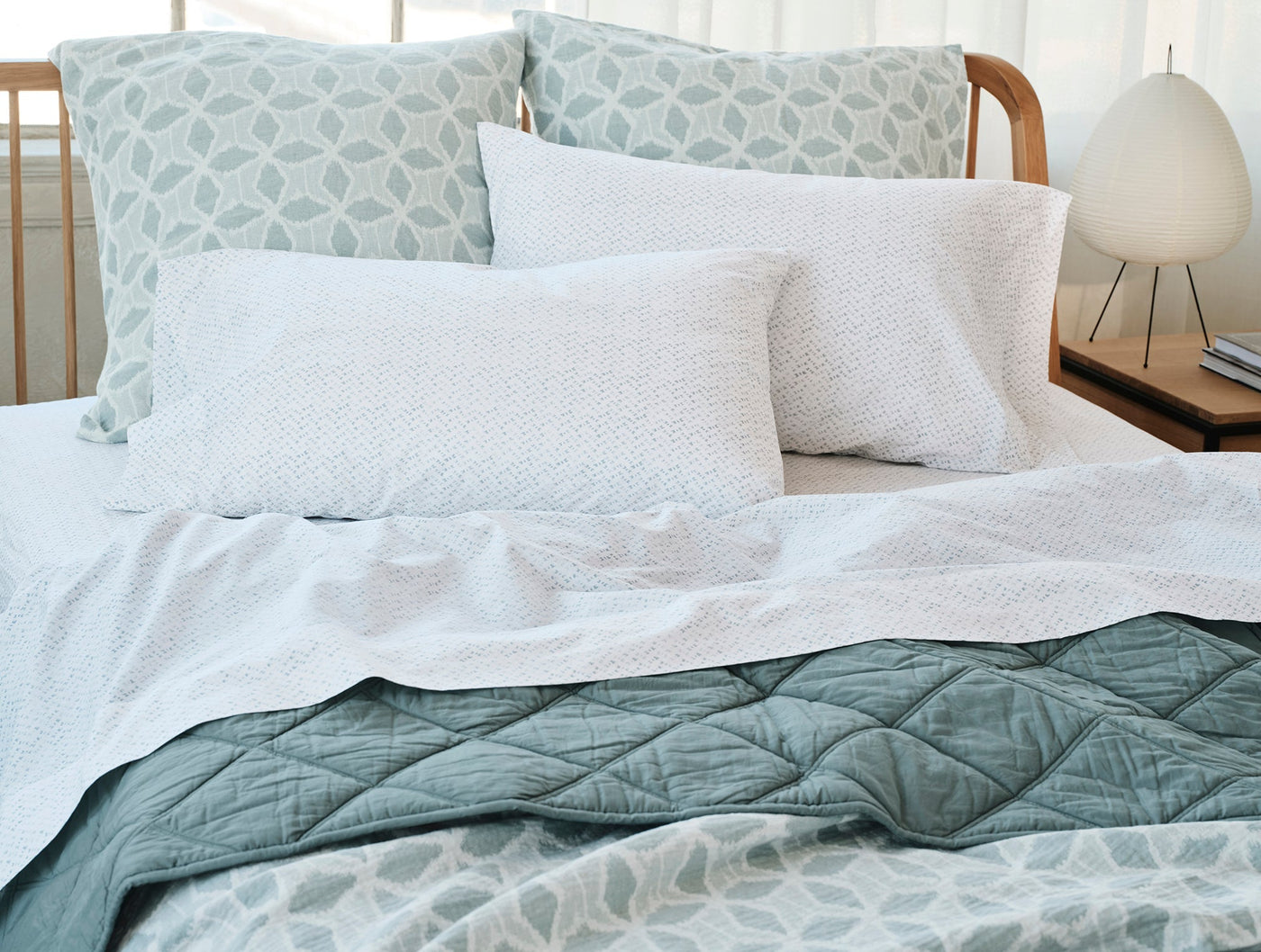 Close-up of white Coyuchi Palomar pillow sham with subtle woven texture on a styled bed.