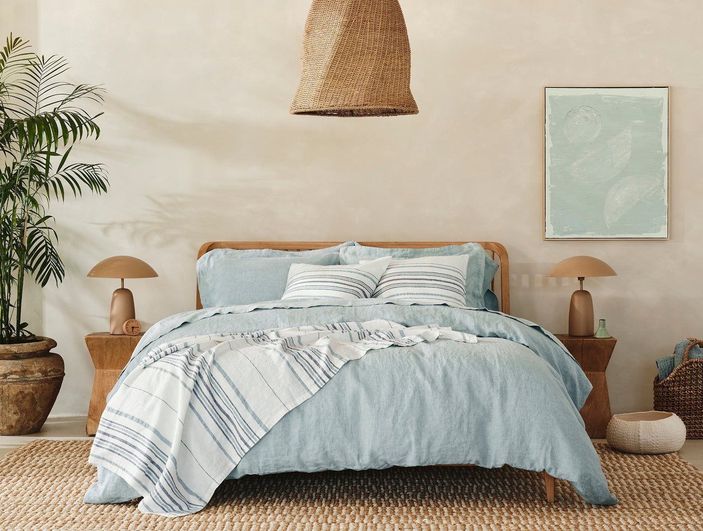 Relaxed Linen duvet cover in pale blue styled on bed with striped throw.