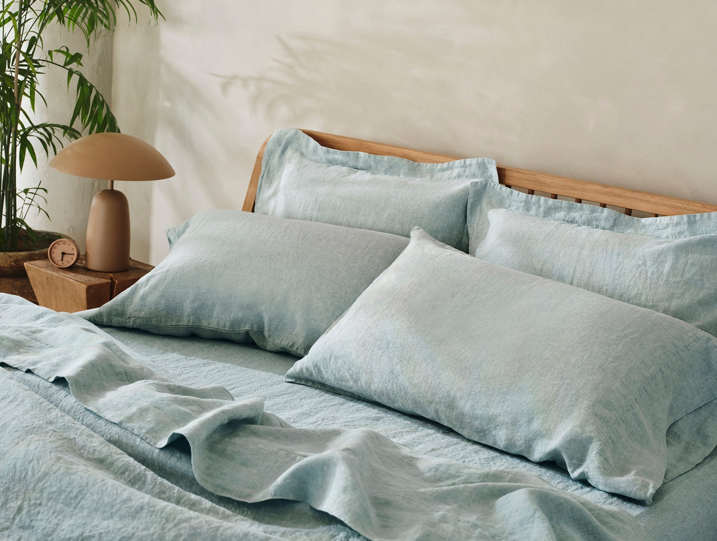 Close-up of Coyuchi Relaxed Linen pillowcases in mist blue on a styled bed.