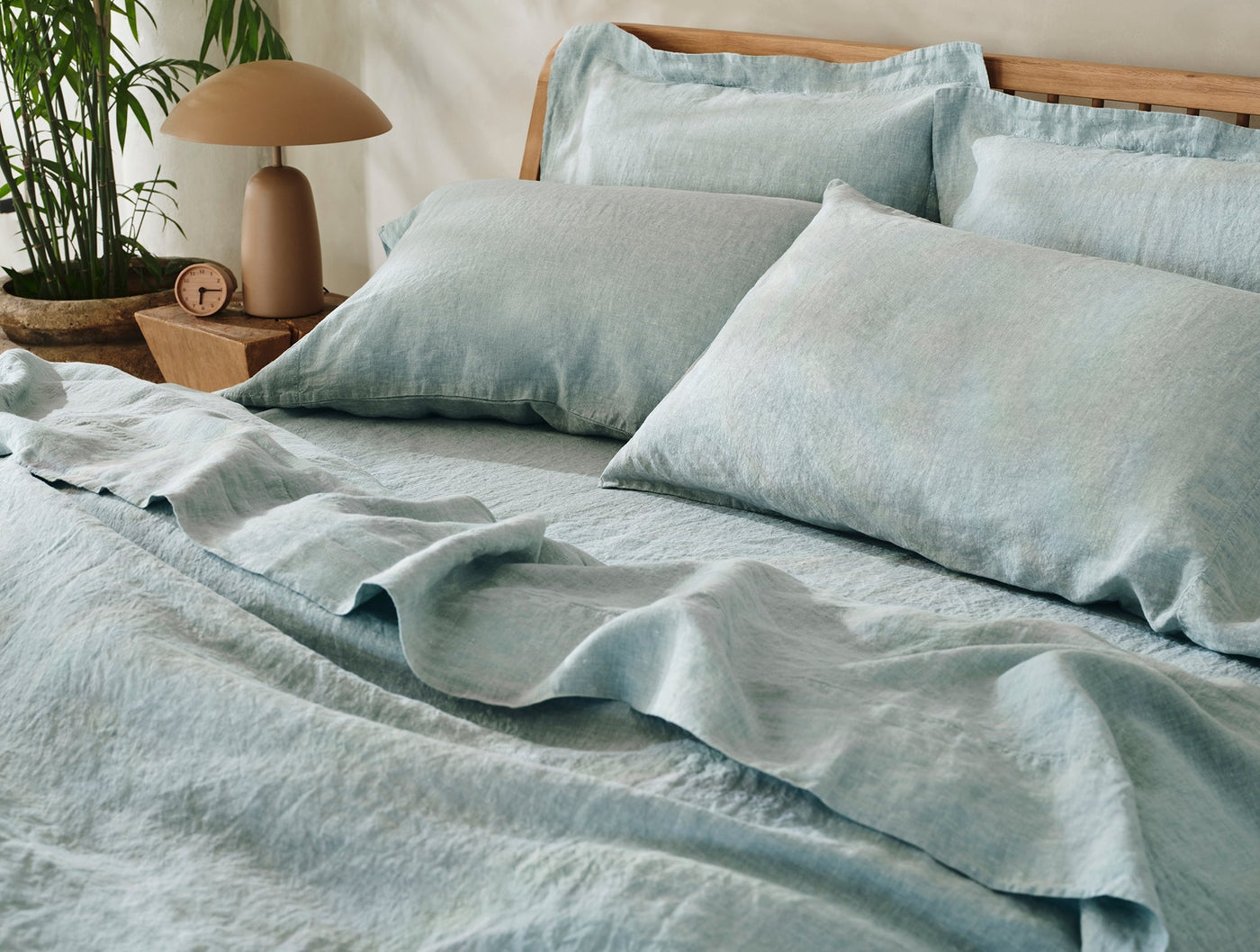 Coyuchi Relaxed Linen sham in pale blue, styled on a made bed with draped duvet.