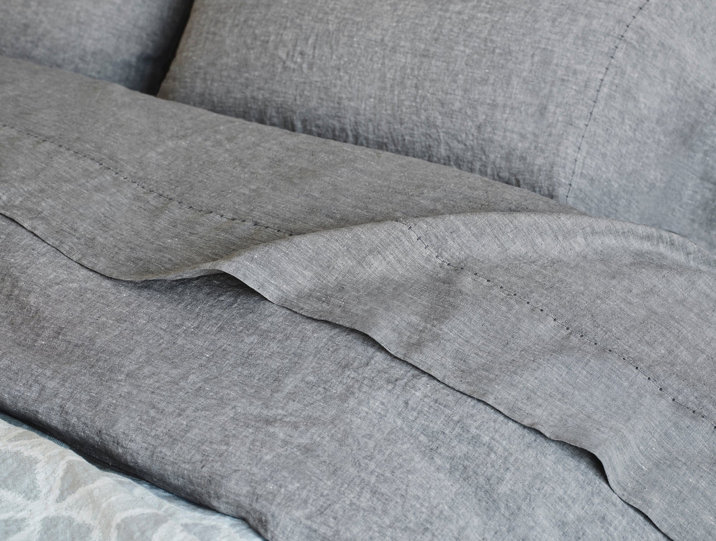 Close-up of Coyuchi Relaxed Linen duvet cover hem detail in heathered gray.