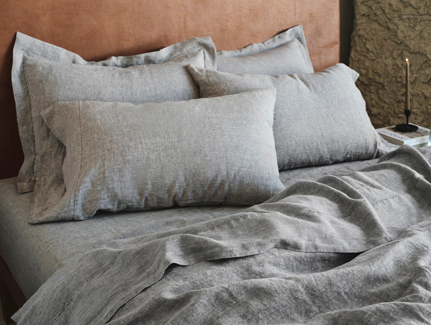 Heathered grey linen bedding styled on bed with layered pillows and draped duvet.
