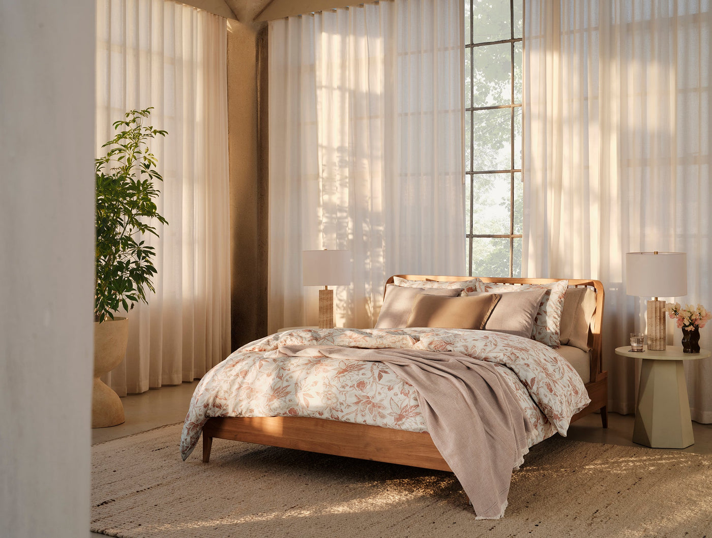 Coyuchi Canyon throw draped across bed foot in warm-toned bedroom with sheer curtains.