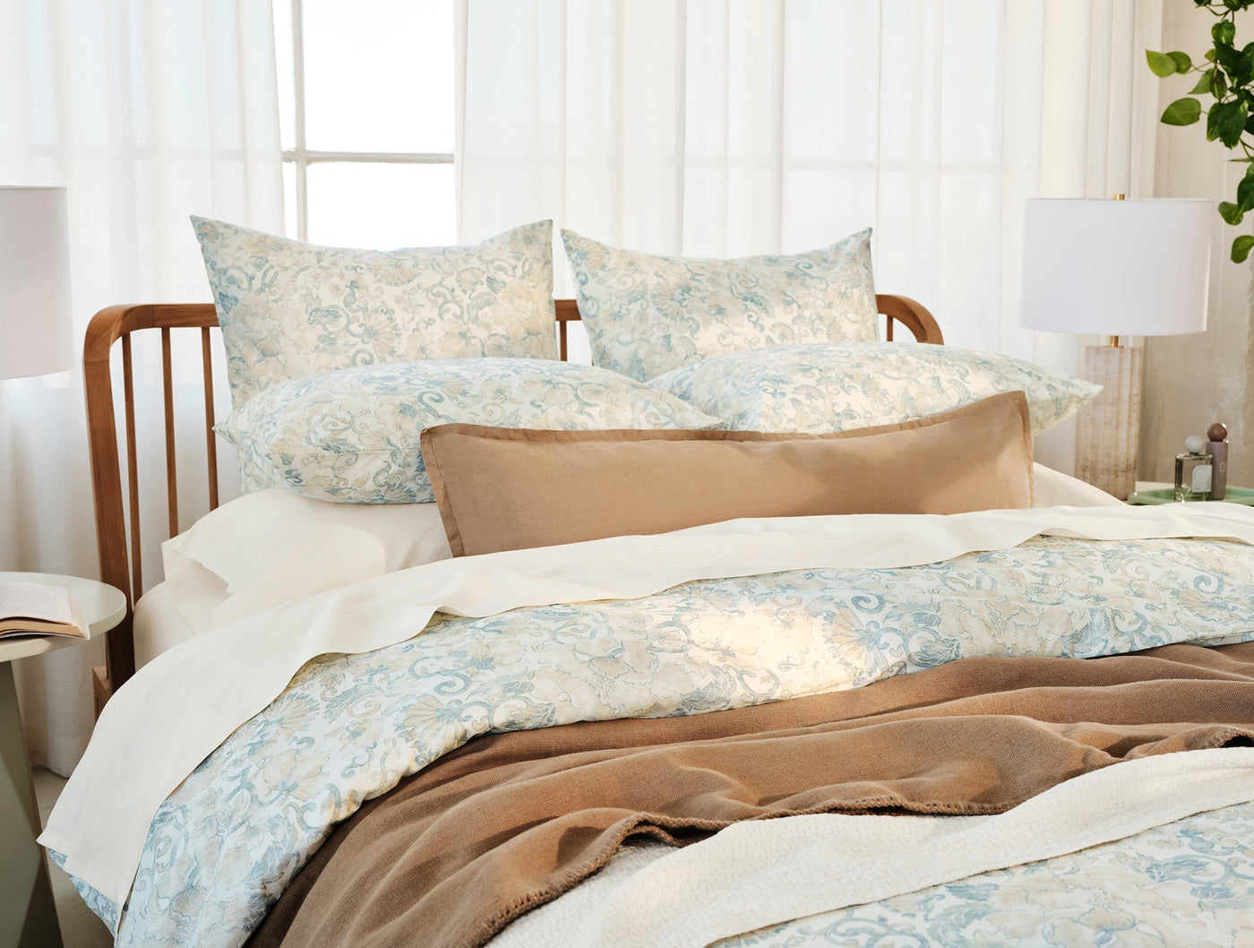 Coyuchi Solana Print duvet cover styled on bed with camel throw and sheer curtains.