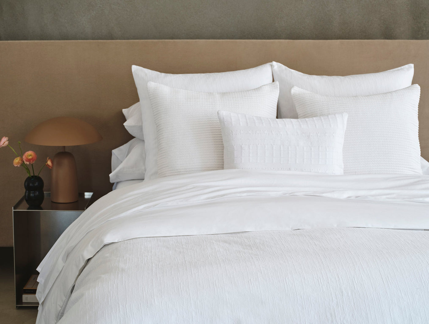 Coyuchi Toro Canyon duvet cover styled on bed with layered white pillows, textured stripe detail.