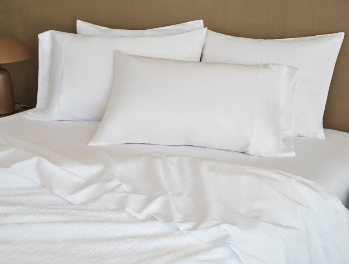 Close-up of white Coyuchi Toro Canyon pillow shams layered on a made bed.