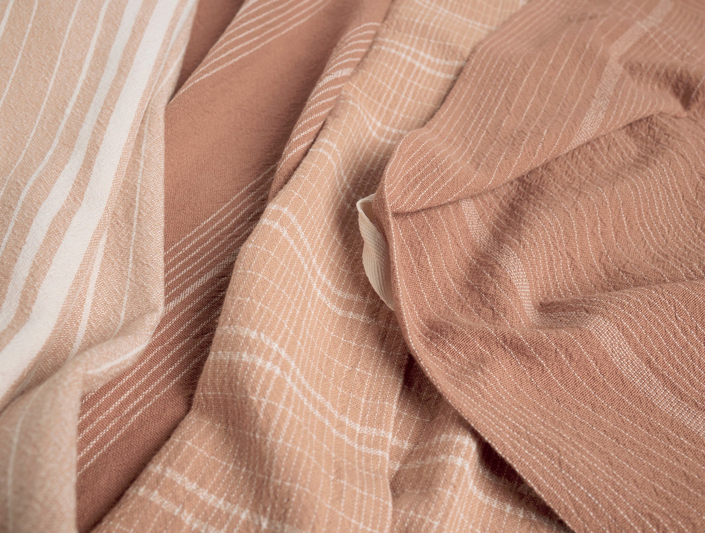 Close-up of Coyuchi Fillmore kitchen towel in terracotta with white stripe weave texture.