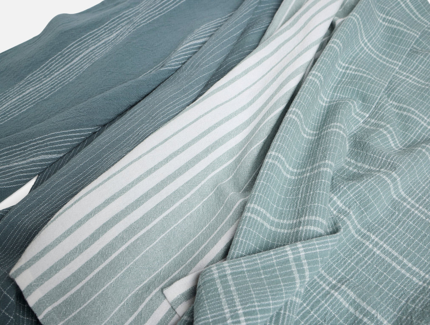 Close-up of Coyuchi Fillmore kitchen towels in sage, showing stripe and grid weave patterns.