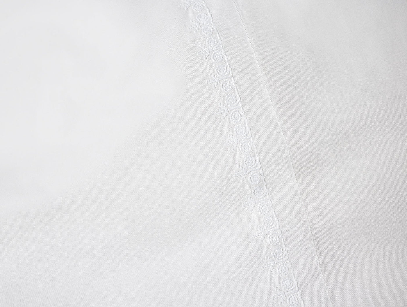 Close-up of Coyuchi Floret white sheet hem with delicate floral embroidered trim detail.
