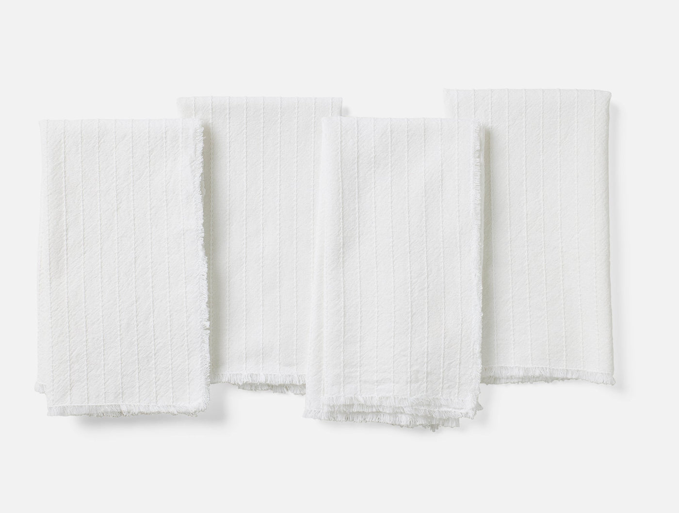 Coyuchi Fringe Stripe napkin set of four in white with ribbed texture and fringe trim.