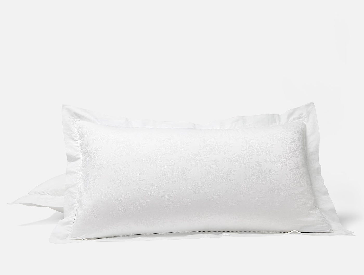 Close-up of white Coyuchi Heirloom Sateen Jacquard pillow sham with flange edge.