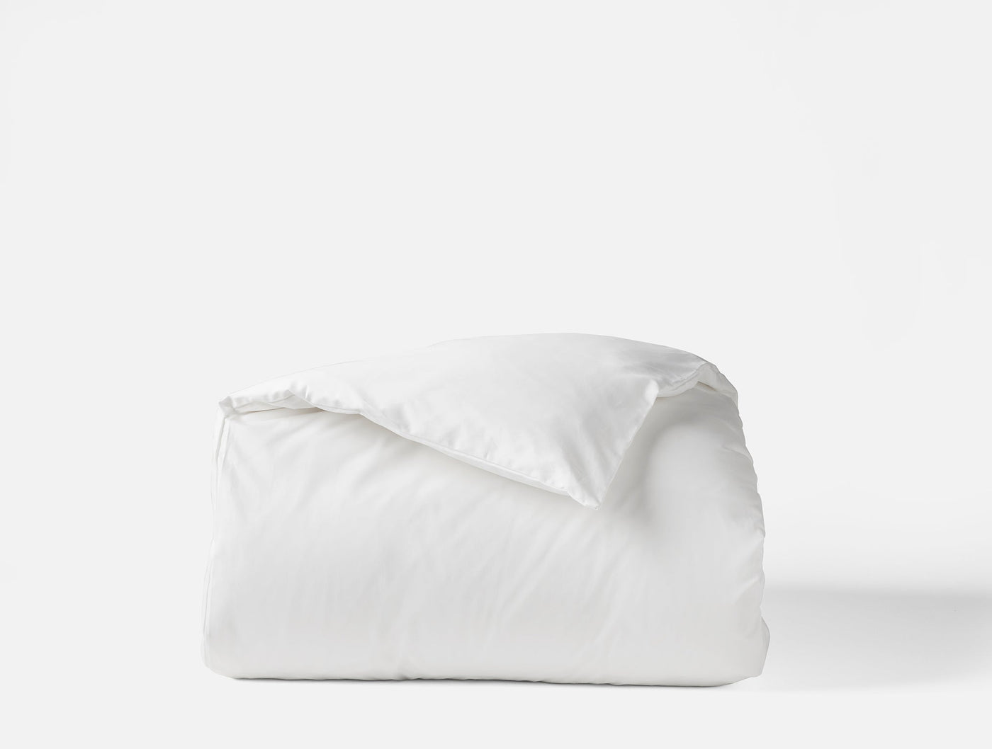 Coyuchi Heirloom Sateen duvet cover in white, neatly folded against a light background.