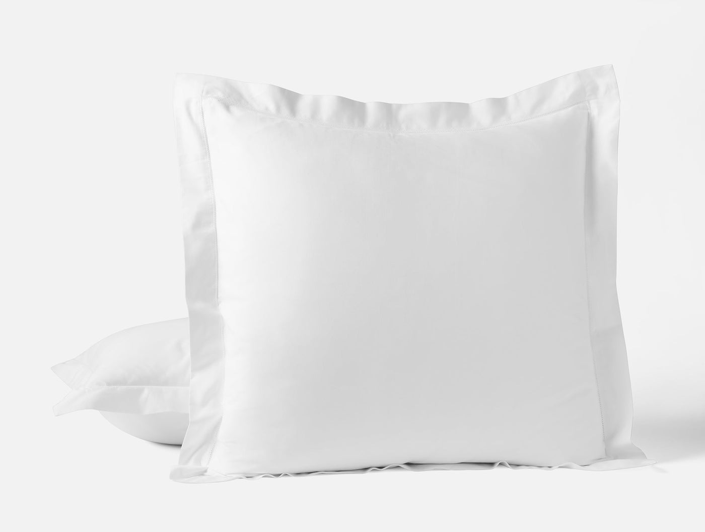 Close-up of Coyuchi Heirloom Sateen pillow sham in white with a classic flange border.